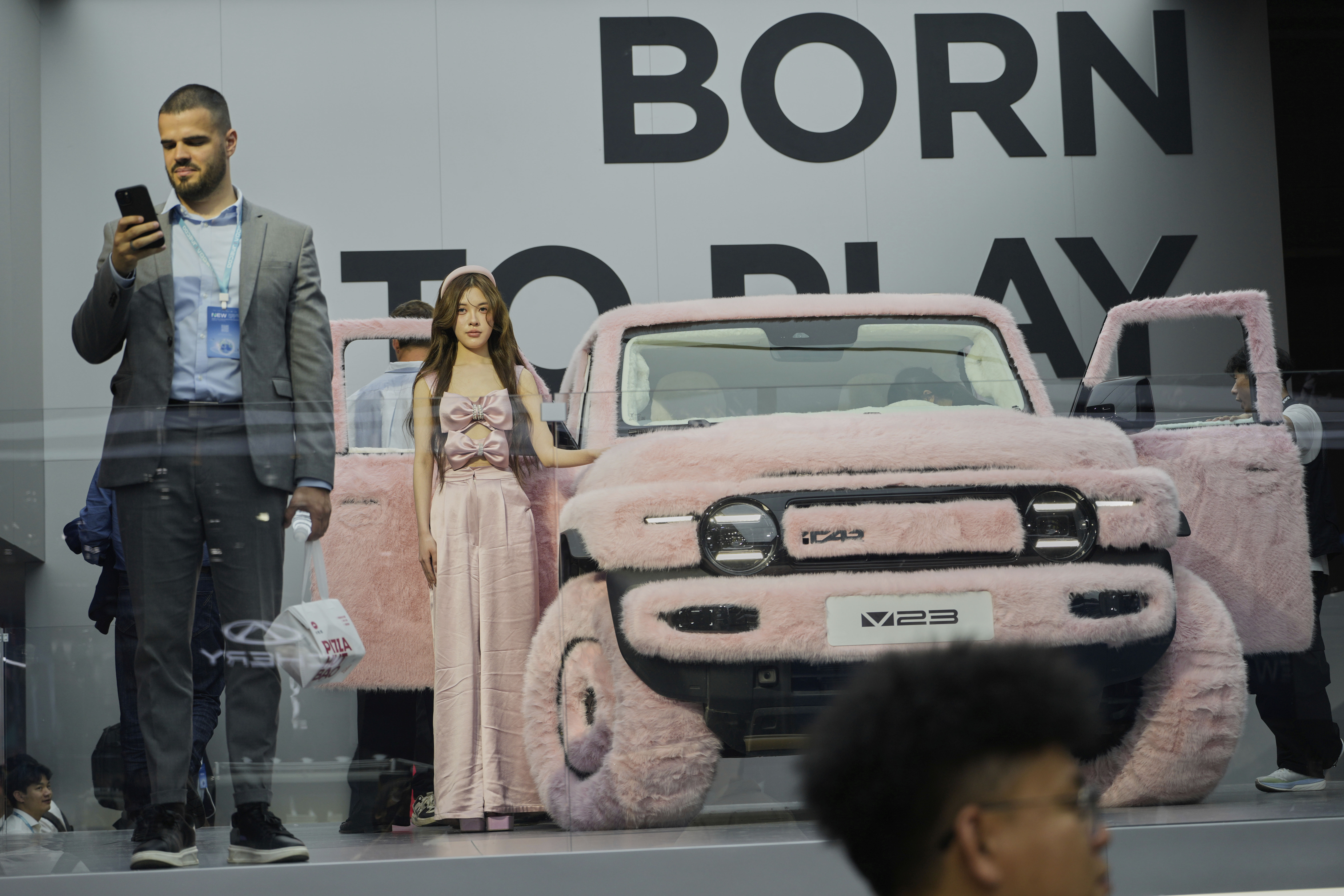 A woman stands next to a iCar 23 decked out with pink fur at the Shanghai auto show on Wednesday, April 23, 2025. (AP Photo/Ng Han Guan)