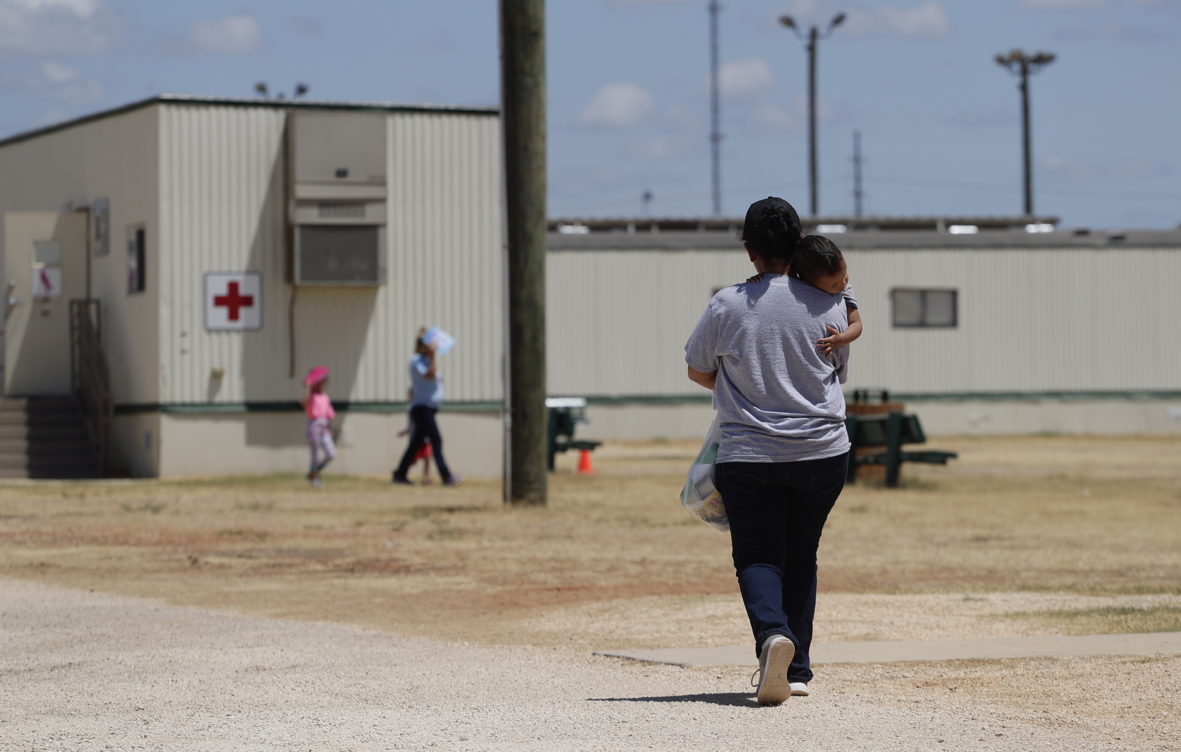 FILE - Immigrants seeking asylum walk at the ICE South Texas Family Residential Center, Aug. 23, 2019, in Dilley, Texas. (AP Photo/Eric Gay, File)