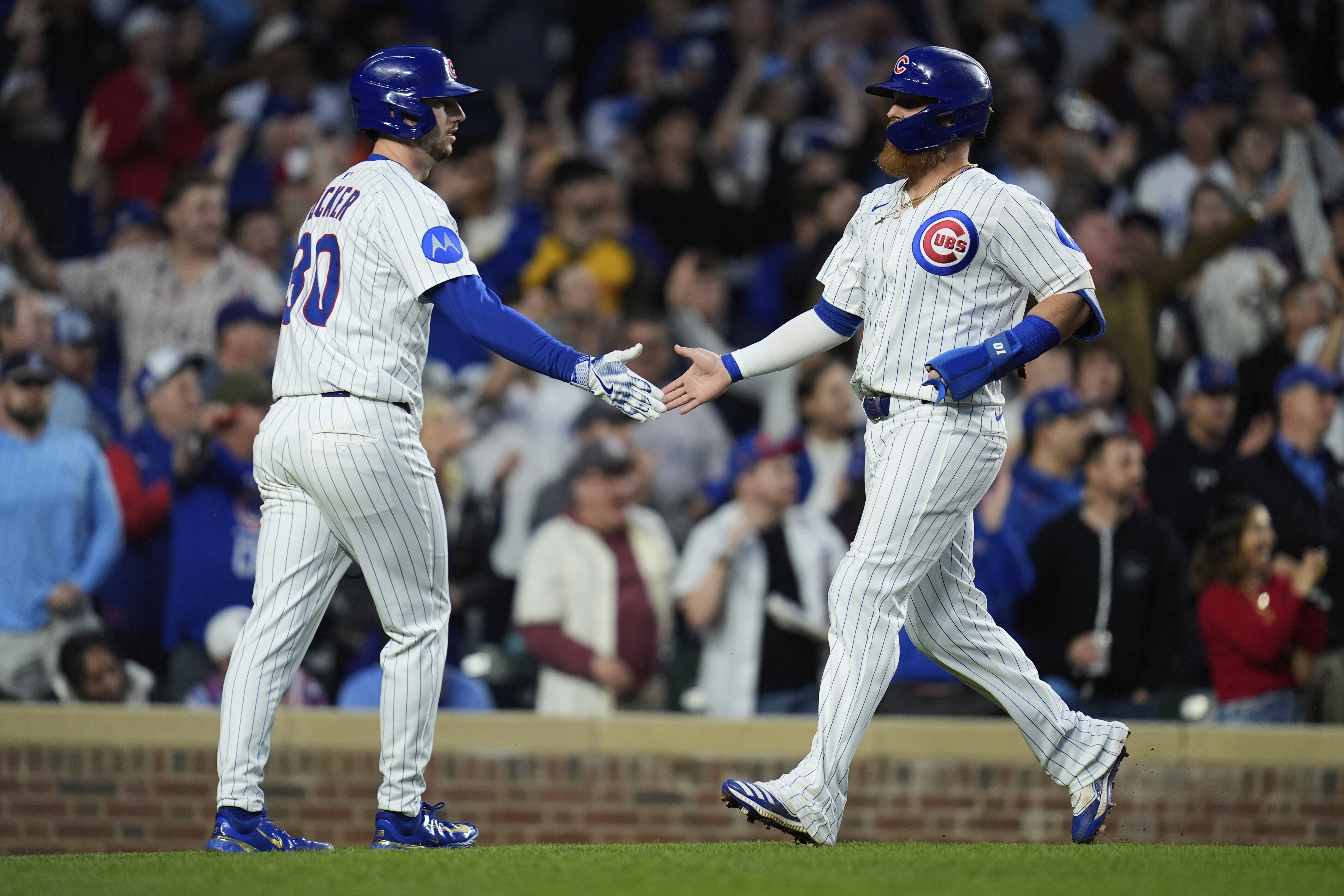 Chicago Cubs Kyle Tucker (30), left, and Justin Turner celebrate after both scoring on a single from Dansby Swanson during the fifth inning of a baseball game against the Los Angeles Dodgers, Wednesday, April 23, 2025, in Chicago. (AP Photo/Erin Hooley)