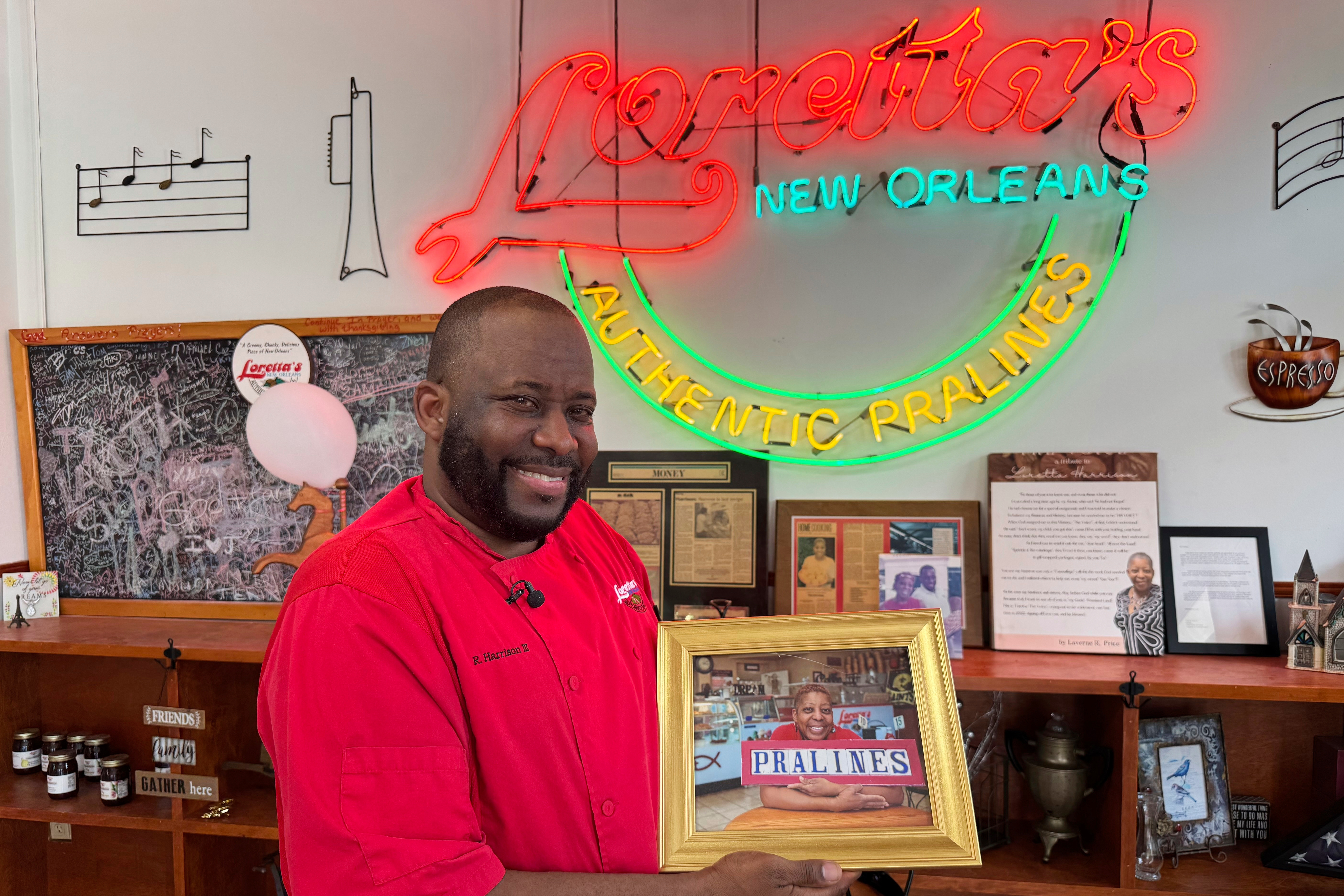 Robert Harrison III, Loretta's Pralines president and CEO, holds a portrait of his mother on Tuesday, April 22, 2025, as he prepares thousands of pralines for the New Orleans Jazz and Heritage Festival. (AP Photo/Jack Brook)